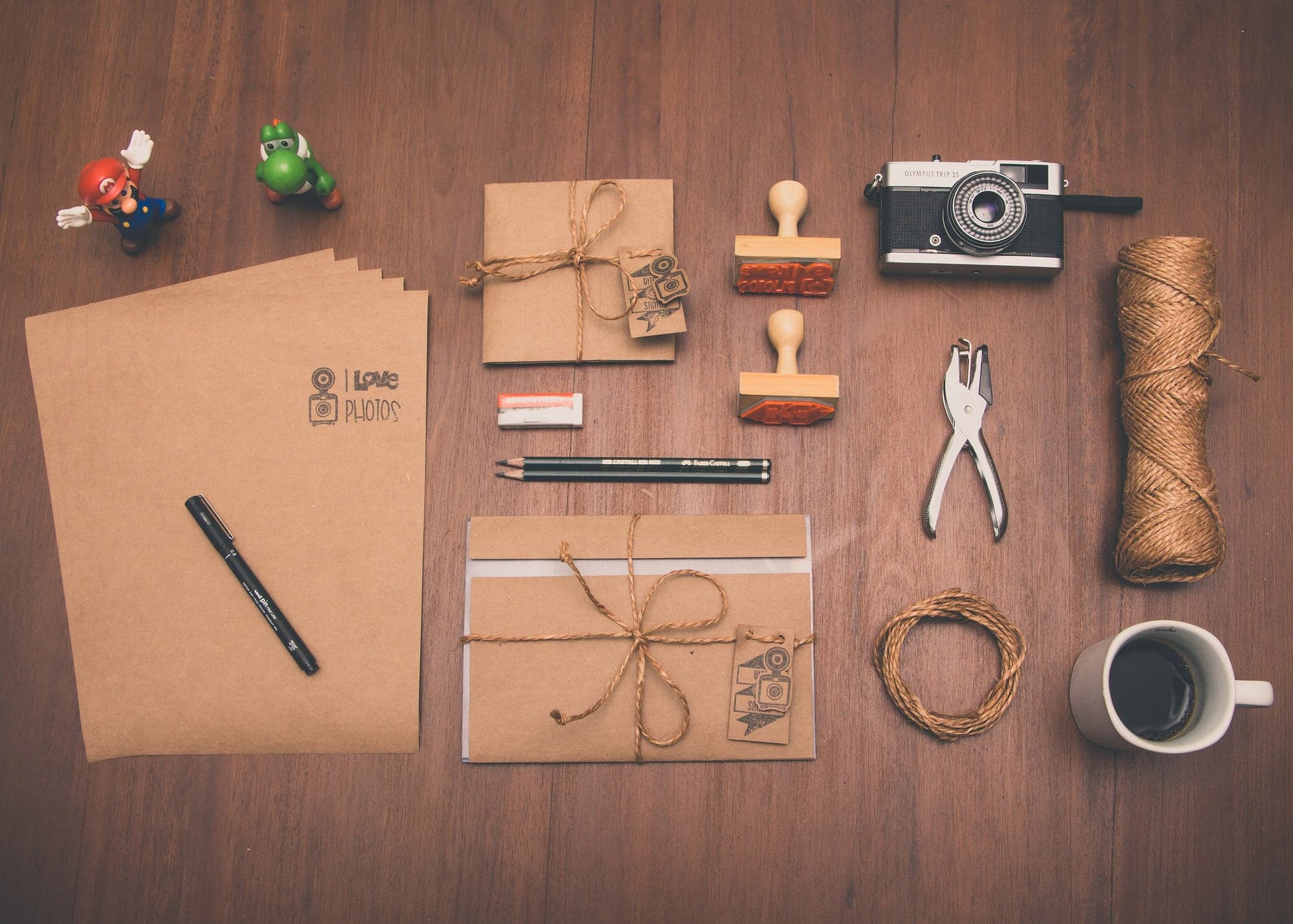 Colis en papier kraft ficelés, tampons et étiquettes posés sur une table en bois.